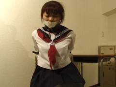Ponytailed asian college girl in uniform in special leather bondage trying to get free