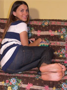 Playful cutie in tight jeans showing her lovely feet on the sofa.